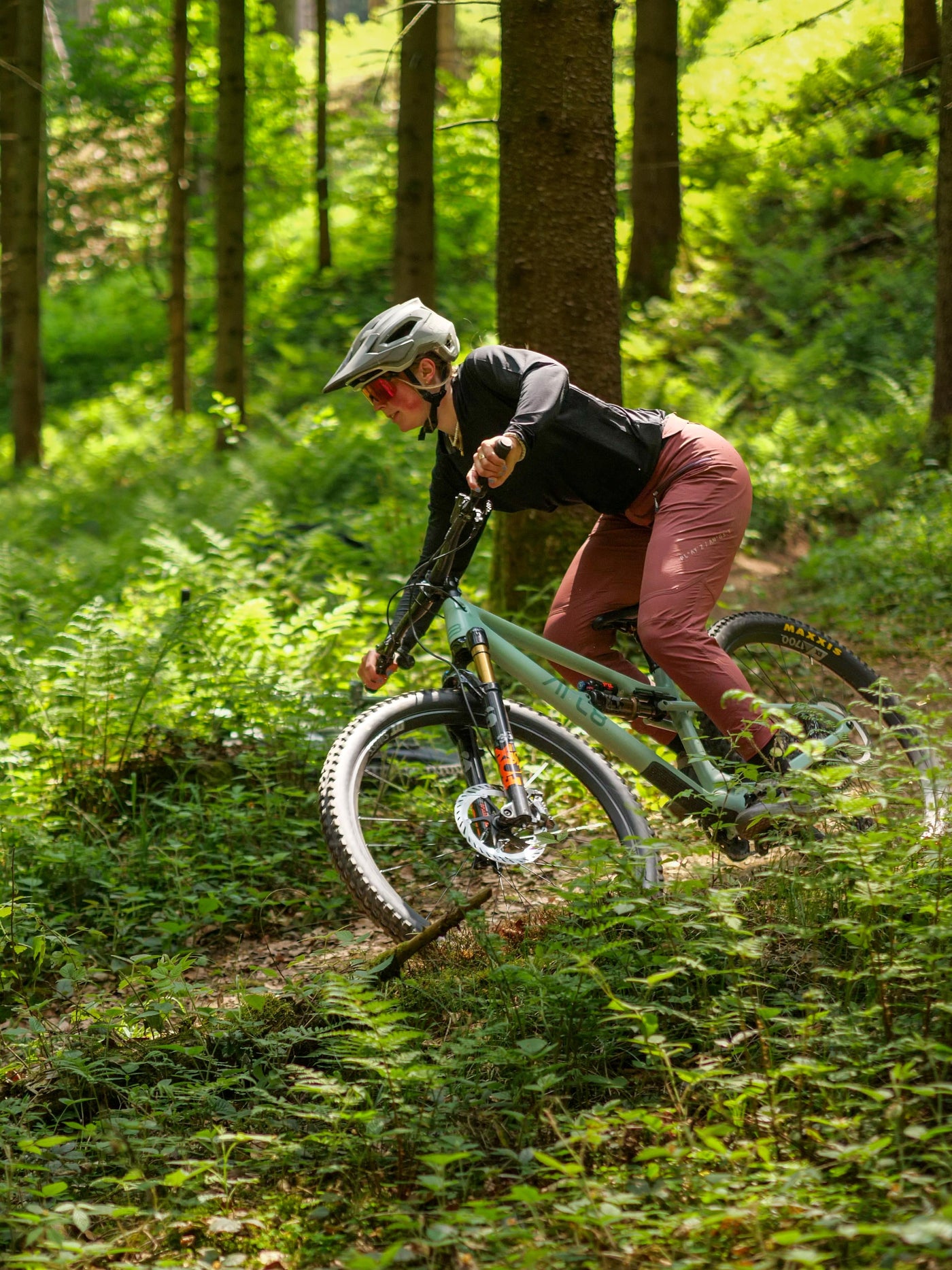 Leni auf einem MTB mit roter Platzangsthose und schwarzen Jersey im Wald
